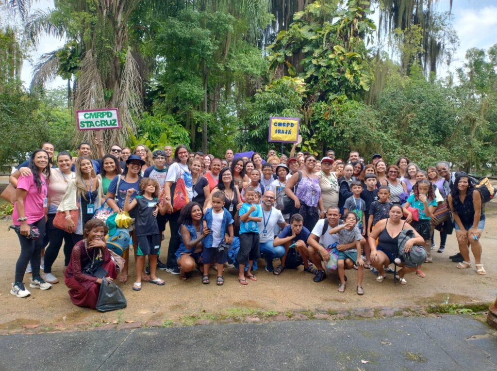 Crianças e adultos com deficiência participando de atividade ao ar livre em colônia de férias no Rio de Janeiro, promovendo inclusão.