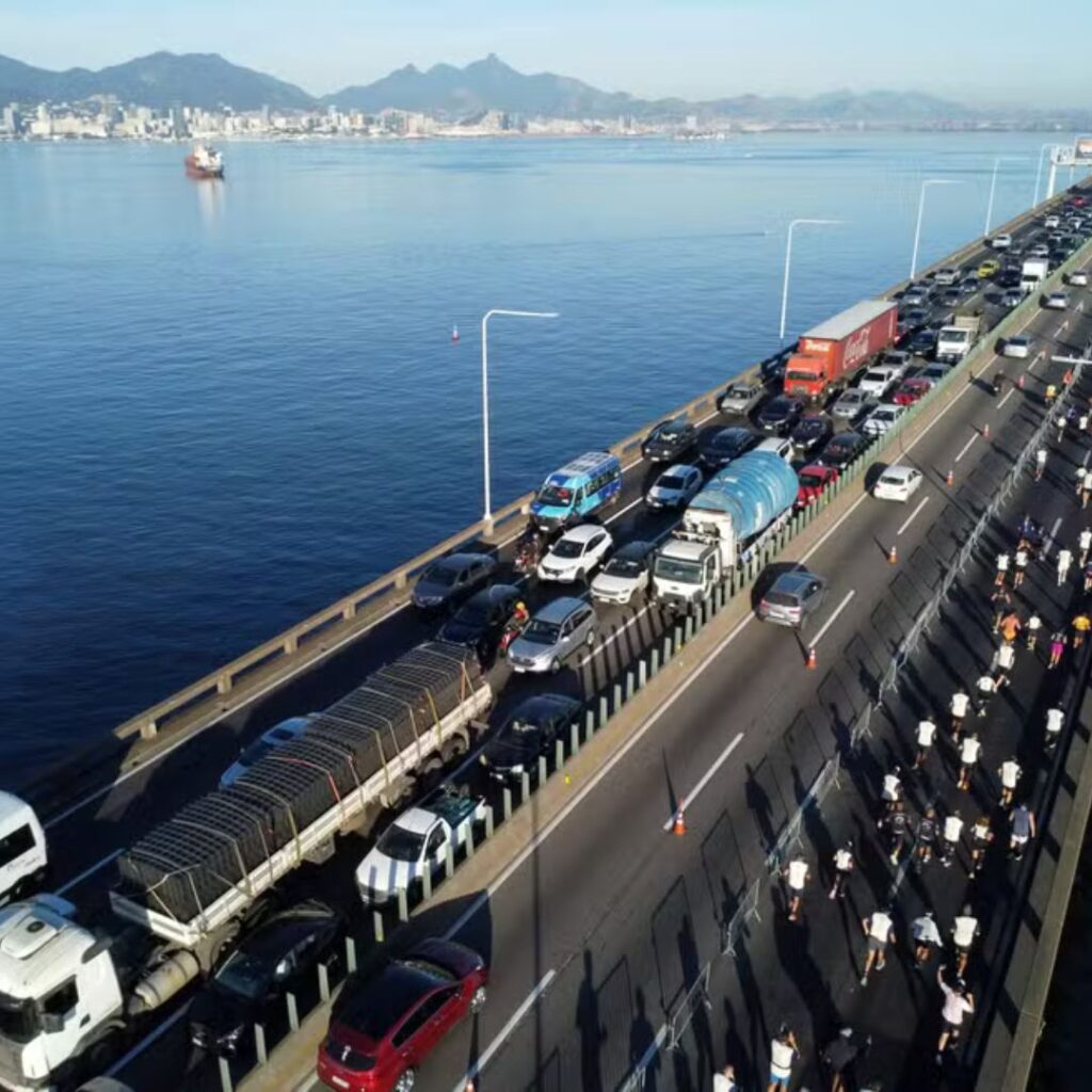 Corredores de rua atravessando a Ponte Rio-Niterói durante a corrida Desafio da Ponte, com a Baía de Guanabara ao fundo.