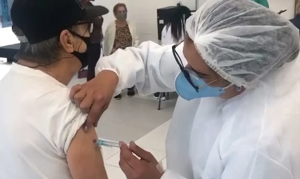 Profissional de saúde segurando frasco da vacina contra Covid-19 atualizada.